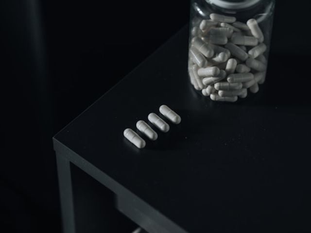 A bottle of supplement capsules on a black table