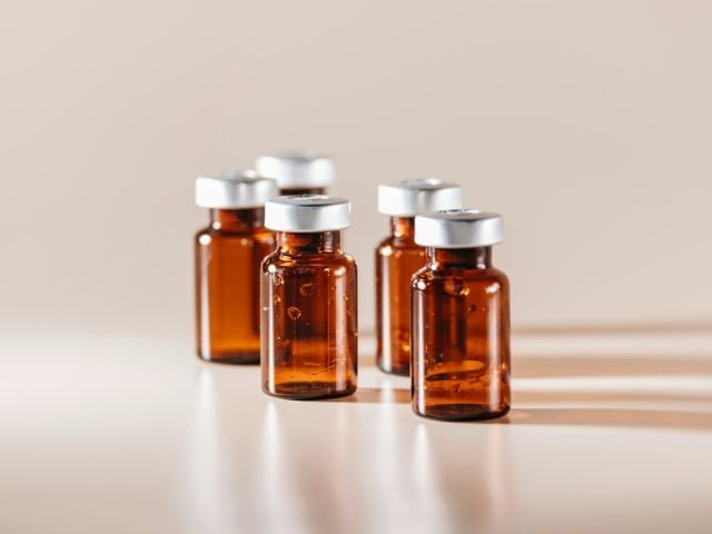 NAD vs peptides featured image showing peptide vials on a counter in dramatic lighting