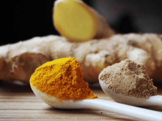 An image of ginger and turmeric powder with ginger roots on the background