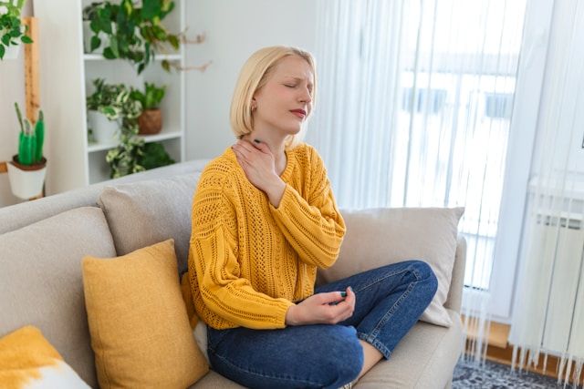 Woman with fibromyalgia neck pain sitting on her couch
