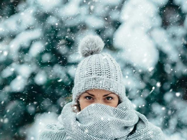 A woman dressed for winter in a white tuque outdoors.