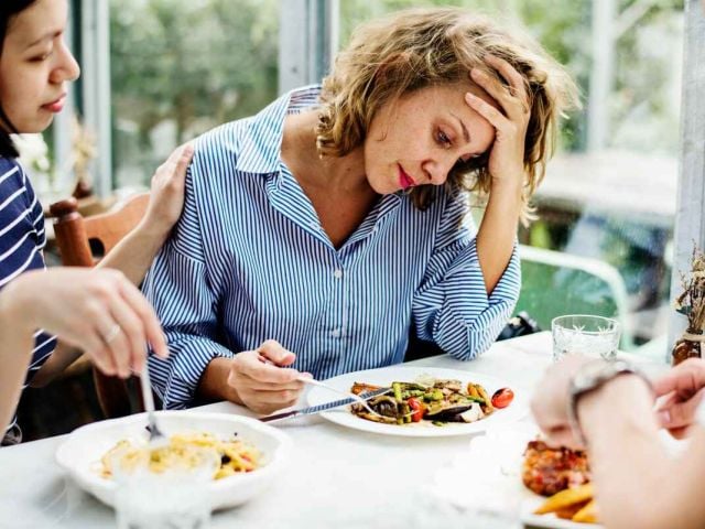 A woman with brain fog after eating holds her head