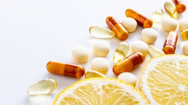 An image of supplement capsules next to a lemon