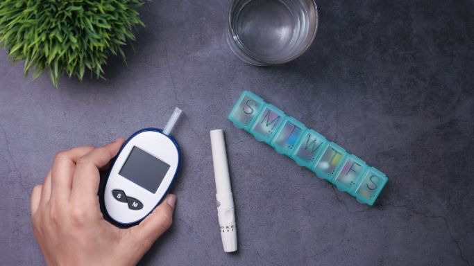 A blood sugar monitor and pill box on a table
