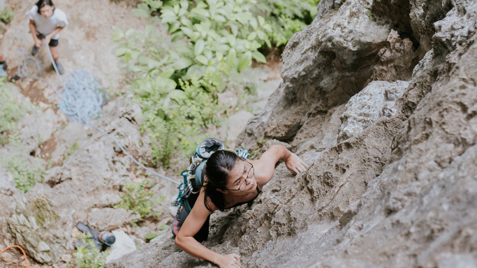 A woman starting a climb at the base of a cliffside