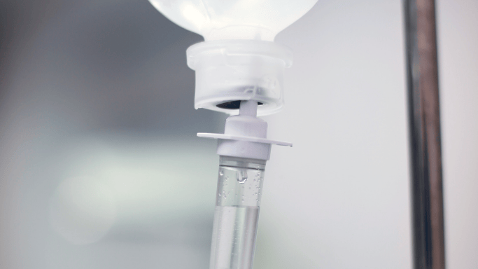 A close-up view of an intravenous (IV) drip chamber with fluid flowing through the tube.