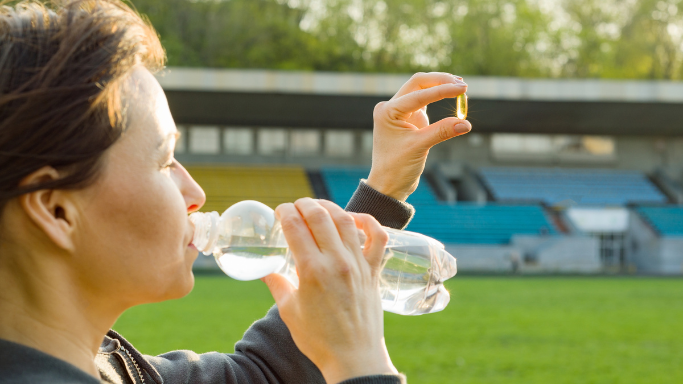 Should You Use Creatine While Dieting or Cutting? 7 An image of a woman drinking water and holding a supplement