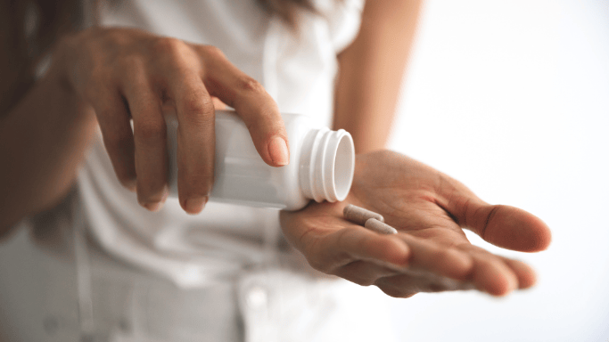 Pros and Cons of Taking Creatine Without Working Out 6 An image of a cannister and a supplement held by a woman