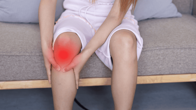 5 Anti-Inflammatory Health Benefits of Ginger Root 4 A woman holding her inflamed knee, showing signs of pain or discomfort.