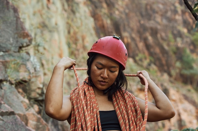 Woman climber with bungee ropes around her and a red helmet