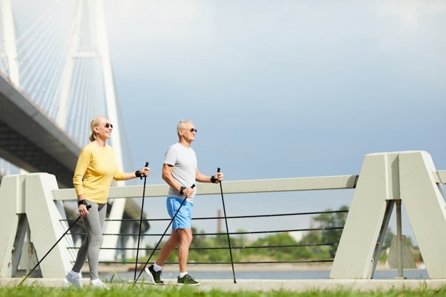 What to Expect Before and After Taking NMN Supplements 3 An older couple with walking poles exercises together on a modern bridge walkway.