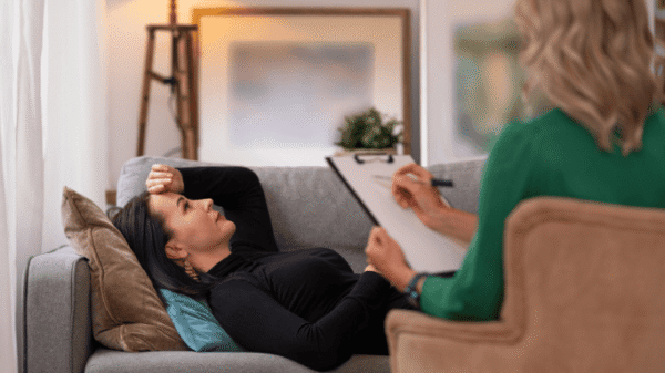 An image of a woman lying on a sofa with a health professional beside her 