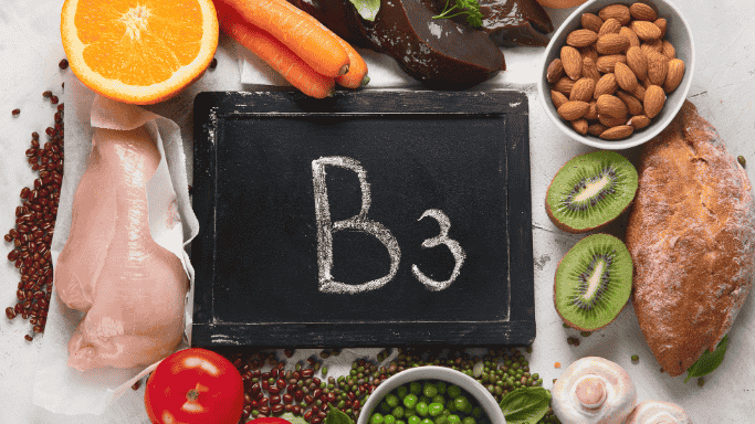 An image of a blackboard with 'B3' written on it, surrounded by various foods that are sources of vitamin B3.
