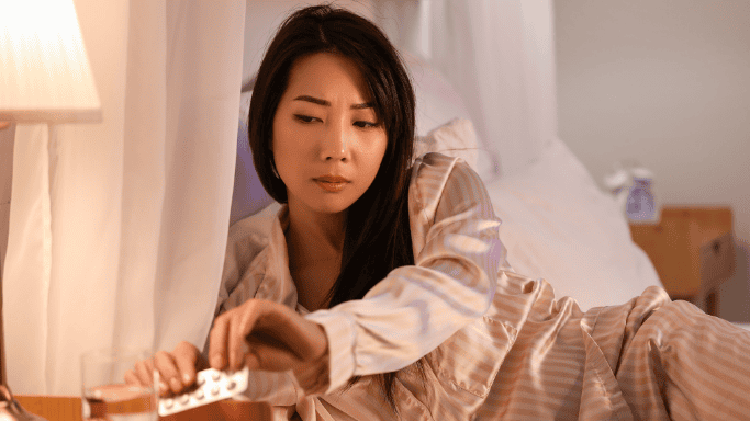 An image of a woman on a bed taking supplement