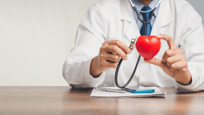 An image of a doctor holding a heart and a stethoscope
