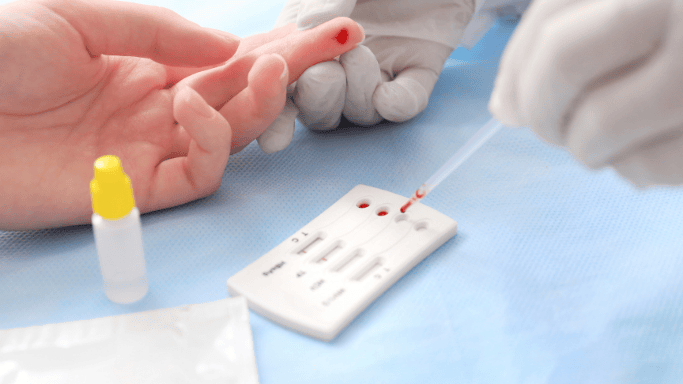An image of a blood test being conducted through a finger prick.