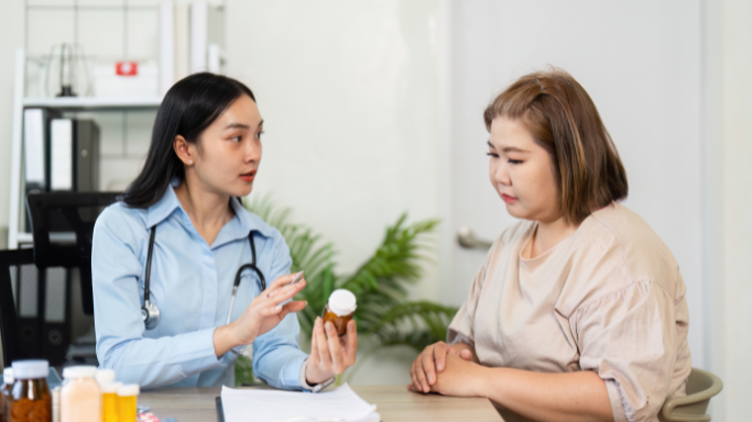 A female doctor holding a supplement bottle and explaining it to a patient during a consultation.