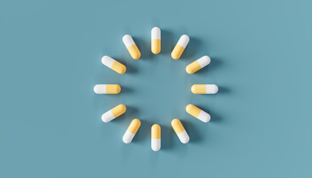White and yellow capsules are arranged in a perfect circle pattern on a soft blue background.