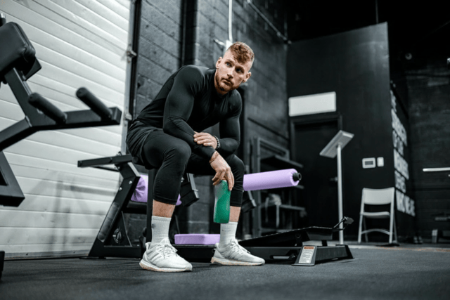 ATP Supplements: Benefits, Dosage and Side Effects 3 A man rests with a water bottle in the gym.