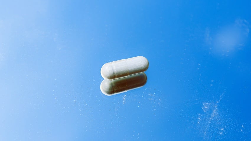 NMN supplement capsule against sky blue background