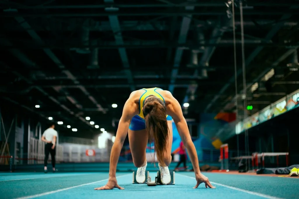 A woman sprinter getting in position before sprinting.