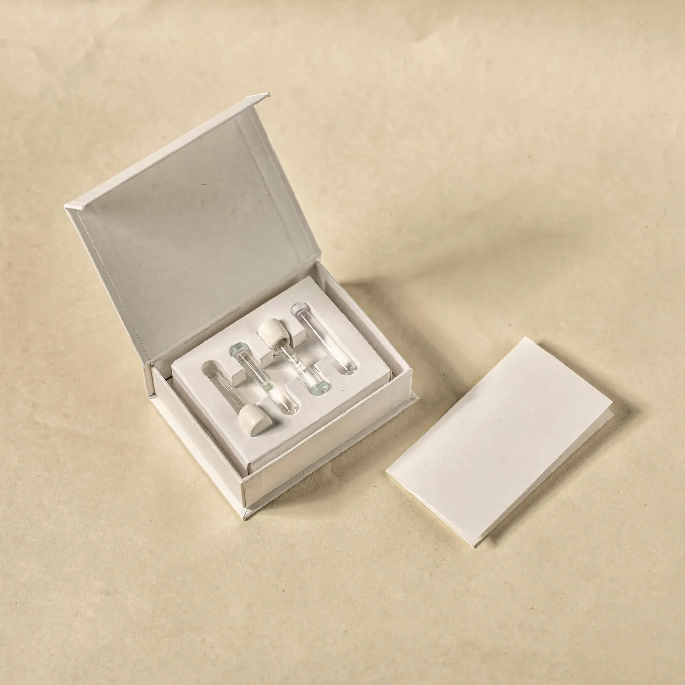 An open white sample collection kit with capped tubes and an instruction card on cream paper